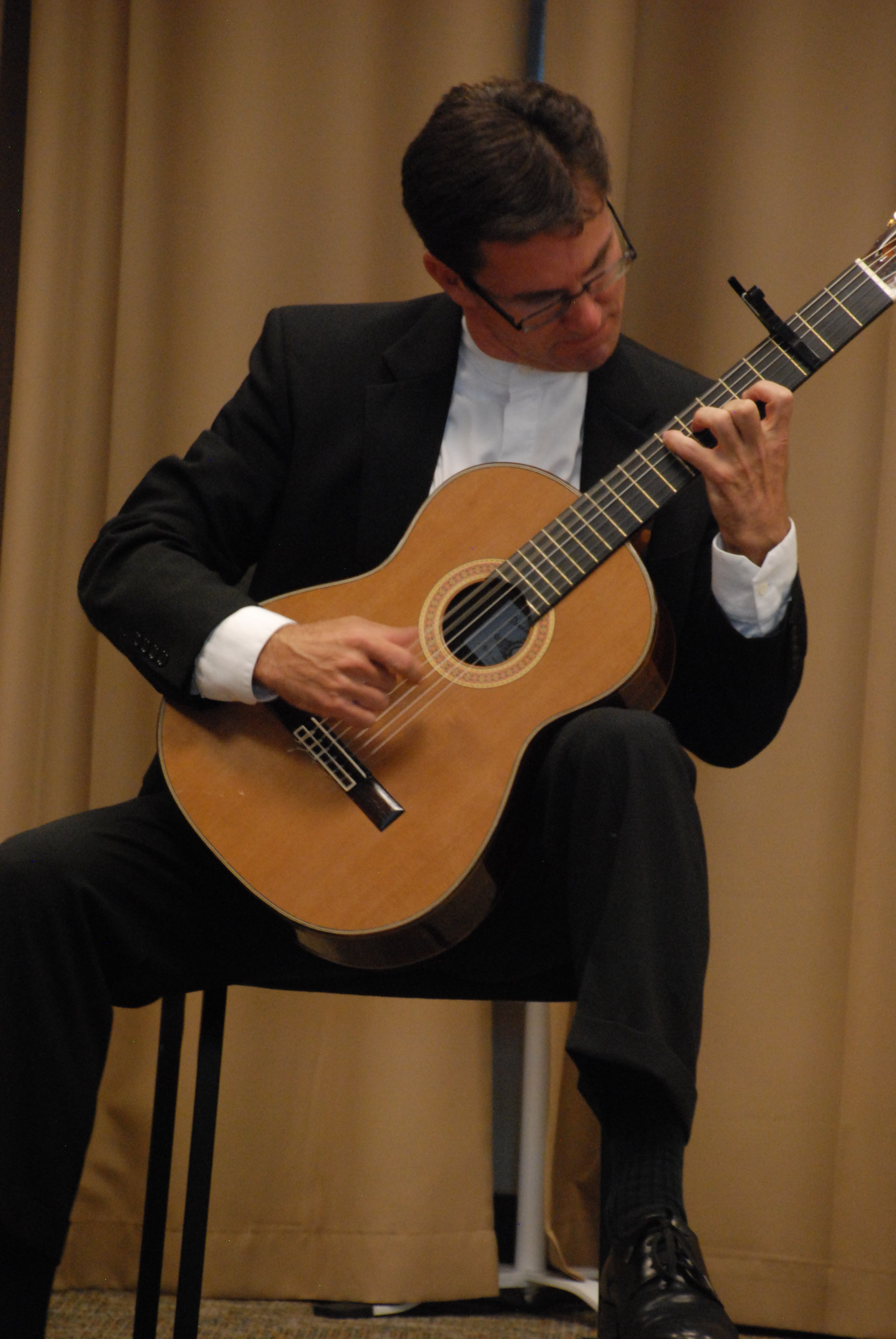 Peter Fletcher, seated, plays an acoustic guitar